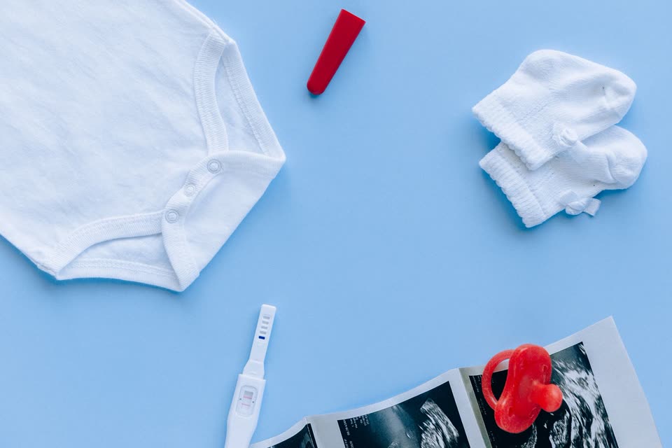 Paket perlengkapan bayi baru lahir: jumper putih, sarung tangan, dan empeng